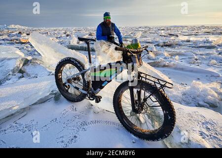 Mann in der Nähe Fahrrad am gefrorenen See bei Sonnenuntergang in Kasachstan Stockfoto