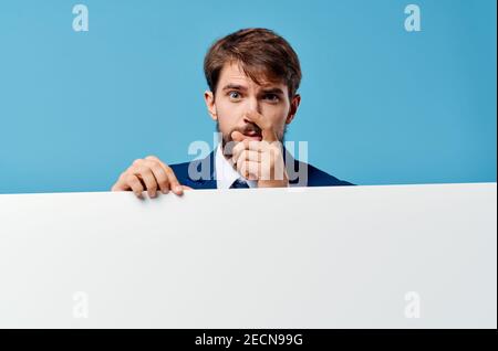 Emotionaler Business-Mann guckt aus hinter Banner abgeschnitten Ansicht Blauer Hintergrund Kopierbereich Stockfoto