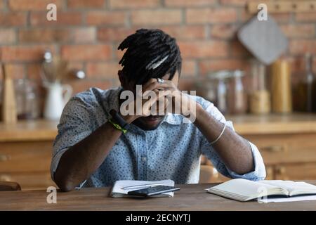 Nahaufnahme deprimiert erschöpft afroamerikanischen Mann am Tisch sitzen Stockfoto