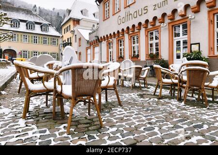 Heidelberg, Deutschland - Februar 2020: Leere Tische mit schneebedeckten Stühlen vor dem Restaurant im historischen Stadtzentrum von Heidelberg Stockfoto