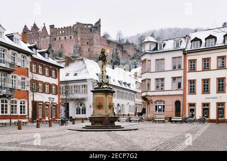 Heidelberg, Deutschland - Februar 2020: Alter Kornmarkt in der Altstadt mit Brunnen und Blick auf das historische Heidelberger Schloss mit Schnee Stockfoto