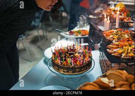 Ältere Frau bläst Geburtstagskuchen mit Kerzen Stockfoto