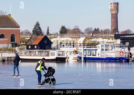 KINDERDIJK, NIEDERLANDE - FEBRUAR 13: Am 13. Februar 2021 wird man in Kinderdijk, Netherla das Winterwetter beim Schlittschuhlaufen auf Natureis beobachten Stockfoto