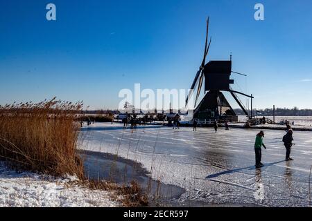 KINDERDIJK, NIEDERLANDE - FEBRUAR 13: Am 13. Februar 2021 wird man in Kinderdijk, Netherla das Winterwetter beim Schlittschuhlaufen auf Natureis beobachten Stockfoto