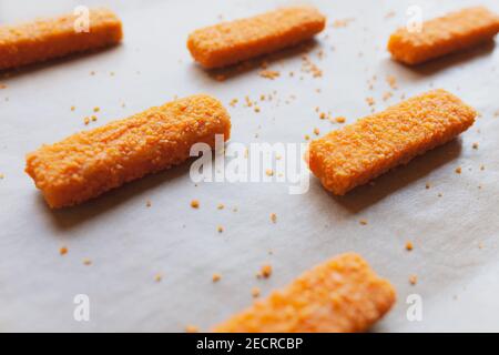 Rohe gefrorene Fischfinger auf Pergamentpapier, fertig zum Backen, mit einigen Krümel Stockfoto