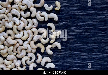 Cashew Haufen auf dunklem Hintergrund. Cashew Foto Tapete. Bio-Lebensmittel rustikal Banner-Vorlage mit Textraum. Schmackhafter gesunder Snack. Verstreute Nüsse auf ta Stockfoto