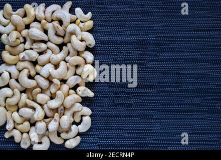 Cashew Stapel auf dunklem Hintergrund. Cashew Foto Tapete. Bio-Lebensmittel rustikal Banner-Vorlage mit Textraum. Schmackhafter gesunder Snack. Verstreute Nüsse auf ta Stockfoto