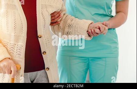 Alte Frau lehnt sich auf Krankenschwester während des Gehens Stockfoto