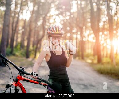 Frau hält Flasche neben Fahrrad Stockfoto