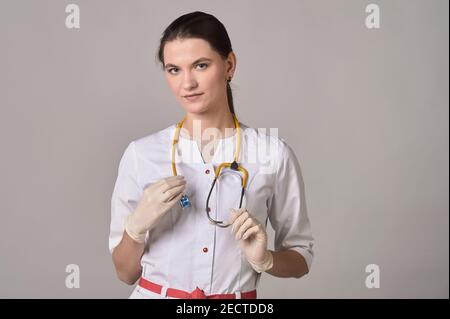 Ärztin mit gelbem Stethoskop und Handschuhen auf dem Hintergrund Stockfoto