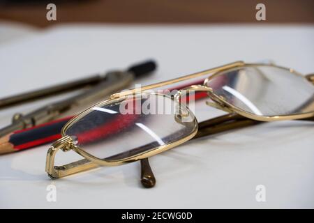 Gläser und Zeichenbedarf liegen auf dem Tisch im Schulzimmer. Universitäre akademische Fächer für Geometrie.Lineal, Kompass, Bleistift und Brille auf Stockfoto
