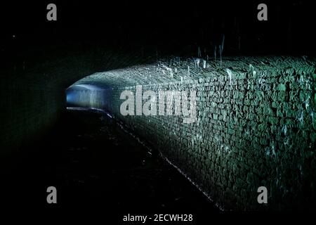 Bekannt als 'The Dark Arch' in der Nähe von Aberford in Leeds. Der Tunnel wurde mit einer Fackel beleuchtet, um die Eiszapfen vom Dach zu zeigen. Stockfoto