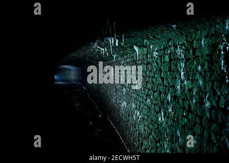 Bekannt als 'The Dark Arch' in der Nähe von Aberford in Leeds. Der Tunnel wurde mit einer Fackel beleuchtet, um die Eiszapfen vom Dach zu zeigen. Stockfoto