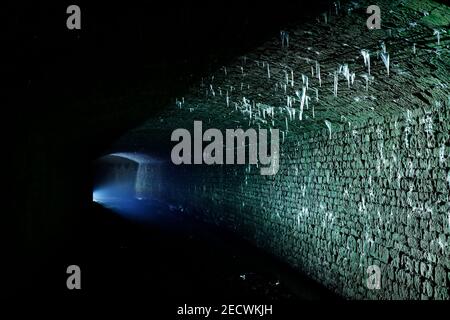 Bekannt als 'The Dark Arch' in der Nähe von Aberford in Leeds. Der Tunnel wurde mit einer Fackel beleuchtet, um die Eiszapfen vom Dach zu zeigen. Stockfoto