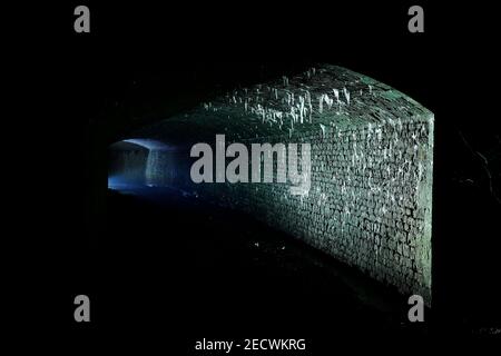 Bekannt als 'The Dark Arch' in der Nähe von Aberford in Leeds. Der Tunnel wurde mit einer Fackel beleuchtet, um die Eiszapfen vom Dach zu zeigen. Stockfoto