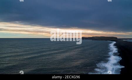 Luftpanorama des schwarzen Strandes Reynisfjara in Richtung Der Kirkjufjara Strand und der Dyrholaey Point bei Sonnenuntergang im Süden Island Stockfoto