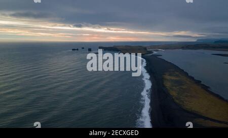 Luftpanorama des schwarzen Strandes Reynisfjara in Richtung Der Kirkjufjara Strand und der Dyrholaey Point bei Sonnenuntergang im Süden Island Stockfoto