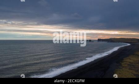 Luftpanorama des schwarzen Strandes Reynisfjara in Richtung Der Kirkjufjara Strand und der Dyrholaey Point bei Sonnenuntergang im Süden Island Stockfoto