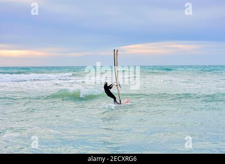 Winter Windsurfen, der Mann im Neoprenanzug im Winter surft, im Hintergrund sieht man die Eisbar Stockfoto