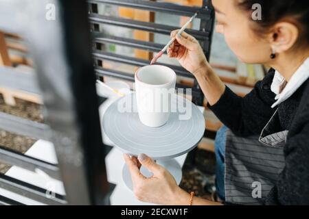 High-Angle-Bild einer Frau Malerei leere Tasse auf Ein Töpfer Rad in einer Werkstatt Stockfoto