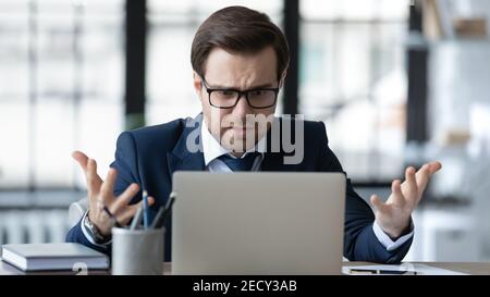 Verärgerte männliche CEO frustriert durch Online-Probleme arbeiten auf Laptop Stockfoto