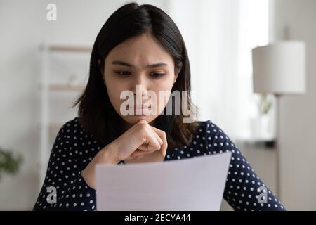 Besorgt junge asiatische Frau lesen offizielle Bankmitteilung über Schulden Stockfoto