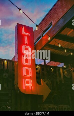 Eine vertikale Aufnahme eines Retro-Neon-Schildes ''Liquor'' zeigt Der Weg zu einer Bar Stockfoto