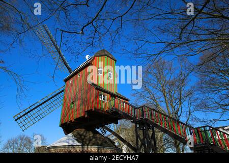 Viersen (Dulken), Deutschland - Februar 9. 2021: Blick über Treppen hinaus auf die rot-grün gestreifte Windmühle (Narrenmühle) gegen den blauen Himmel im Winter Stockfoto