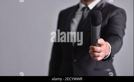 Mann in einem Anzug gibt ein Mikrofon zu sprechen Stockfoto