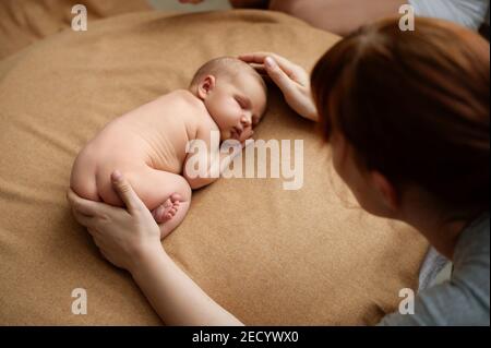 1. Mutter beruhigt ihr Baby bei einem neugeborenen Fotoshooting Stockfoto