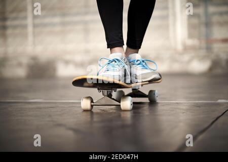 Nahaufnahme der Füße einer jungen Frau beim Skateboarden im Freien Stockfoto