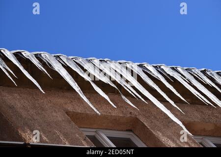 Eiszapfen, die sehr nahe am Rand des Hauses hängen Stockfoto