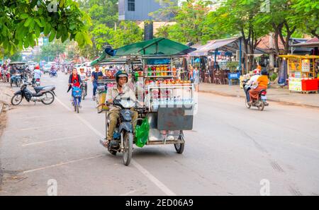 Siem Reap, Kambodscha - 31. März 2018: Verkäufer auf einem Motorrad in der Stadtstraße. Mobiles Lokal auf dem Fahrrad. Imbissstand auf dem Motorrad. Straßenrestaurant auf dem Rad Stockfoto