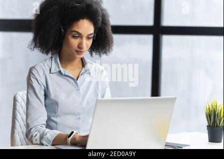 Junge Biracial Frau im Internet surfen, tippen auf dem Computer, chatten, Nachrichten überprüfen, eine Liste von Aufgaben, reden über die Nachrichten, arbeiten aus Stockfoto
