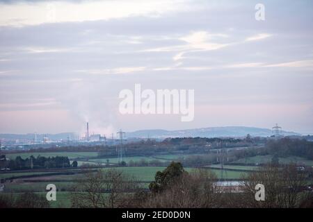 Blick über die Landschaft zum industriellen Avonmouth und dem Seabank Kraftwerk, das Dampf abpumpt, über Windturbinen und Strommasten Stockfoto