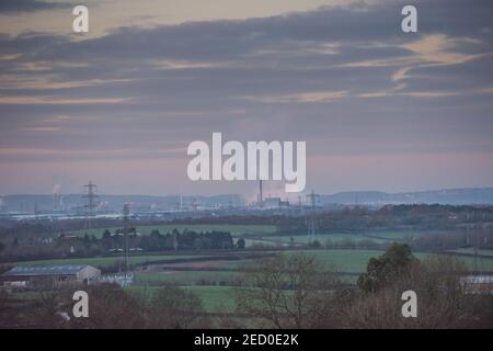 Blick über die Landschaft zum industriellen Avonmouth und dem Seabank Kraftwerk, das Dampf abpumpt, über Windturbinen und Strommasten Stockfoto
