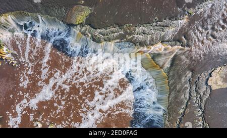 Obere Luftaufnahme des großen Wasserfalls mit rotem Wasser. Stockfoto