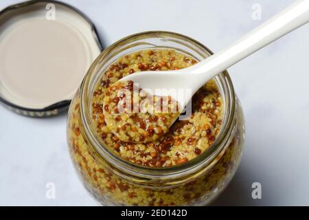 Grobkörniger Senf im Glas mit Löffel, Dijon-Senf, Frankreich Stockfoto