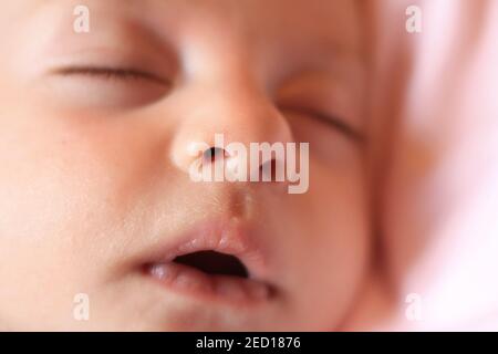 Eine Nahaufnahme des Gesichts eines Neugeborenen, das friedlich mit offenem Mund schläft. Stockfoto
