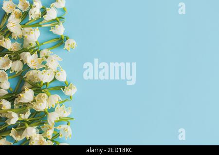 Frühlingsblumen Rand auf blauem Papier flach legen. Stilvolle Grußkarte mit Blumenmuster und Platz für Text. Hallo Frühling. Weißer Frühling Schneeflocken blüht auf blau Stockfoto