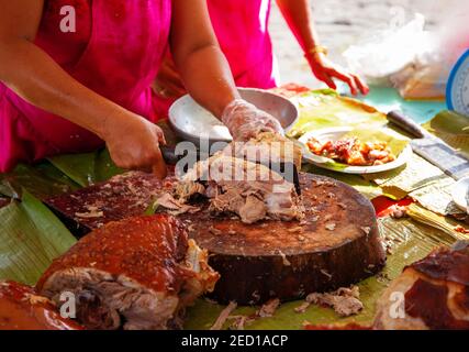 Lechon National philippine Gericht mit Kellnerin Hand. Frau verkauft gebratenes Schweinefleisch in asiatischen Land. Traditionelle Gericht ganze gebratenes Schwein. Köstliches Fleisch gekocht Stockfoto