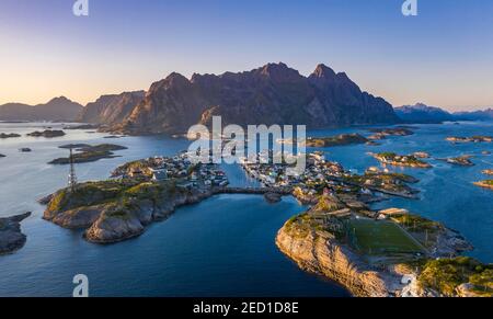 Luftaufnahme, Abendsonne über Henningsvaer mit Fußballstadion, Felseninseln im Meer vor Bergen, Festvagtinden, Vestvavoy, Lofoten, Nordland Stockfoto