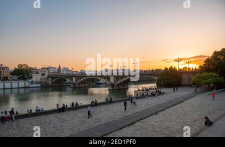 Uferpromenade Muelle de la Sal am Rio Guadalquivir mit Brücke Puente de Triana, Sonnenuntergang, Sevilla, Andalusien, Spanien Stockfoto