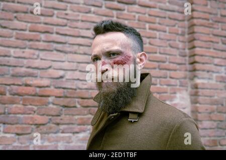Seitenansicht Hipster Mann mit Bart und Kino Make-up posiert Auf der Straße Stockfoto