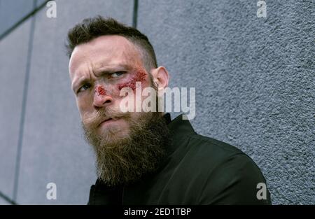 Seitenansicht Hipster Mann mit Bart und Kino Make-up posiert Auf der Straße Stockfoto