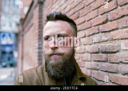 Seitenansicht Hipster Mann mit Bart und Kino Make-up posiert Auf der Straße Stockfoto
