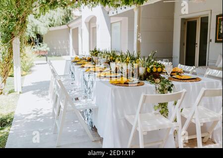 Eleganter Tisch mit Kompositionen aus Zitronen und leerem Geschirr Vorbereitet für Bankett im Sommergarten Stockfoto