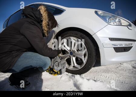 Seitenansicht niedriger Winkel der anonymen weiblichen Fahrer Wechselrad Von Auto im Winter Stockfoto