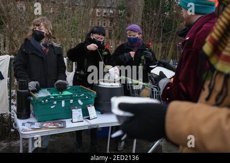 Glasgow, Großbritannien, am 14. Februar 2021. Drei Freiwillige der Organisation "Food not Bombs (Glasgow)" geben heiße Suppe und vegane Haggis im Queen's Park aus. Dies ist das Wochenende 4th des Standes, der Nahrung, gespendet von lokalen Unternehmen, für jeden, der es wünscht, und Kleidung für die Bedürftigen, in der Stadt Southside während der aktuellen Coronavirus Covid-19 Gesundheitspandemie. Foto: Jeremy Sutton-Hibbert/ Alamy Live News. Stockfoto