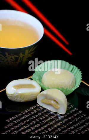 Mochis mit Tee und Essstäbchen, japanischer klebriger Reiskuchen mit grünem Tee-Geschmack, asiatische Süßwarenspezialität Stockfoto